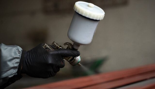 Foto com foco em uma mão que está aplicando coil coating